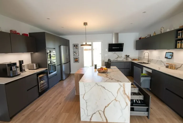 Cuisine moderne en U/L avec îlot central, meubles noirs et plan marble.Équipements: réfrigérateur, four, micro-ondes, cafetière. Rangements optimisés, rangement tiroirs, espace dégagé. Idéal aménagement petite cuisine 6m2.